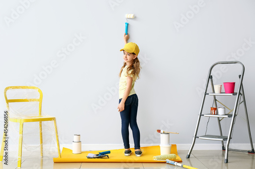 Little girl painting wall in room
