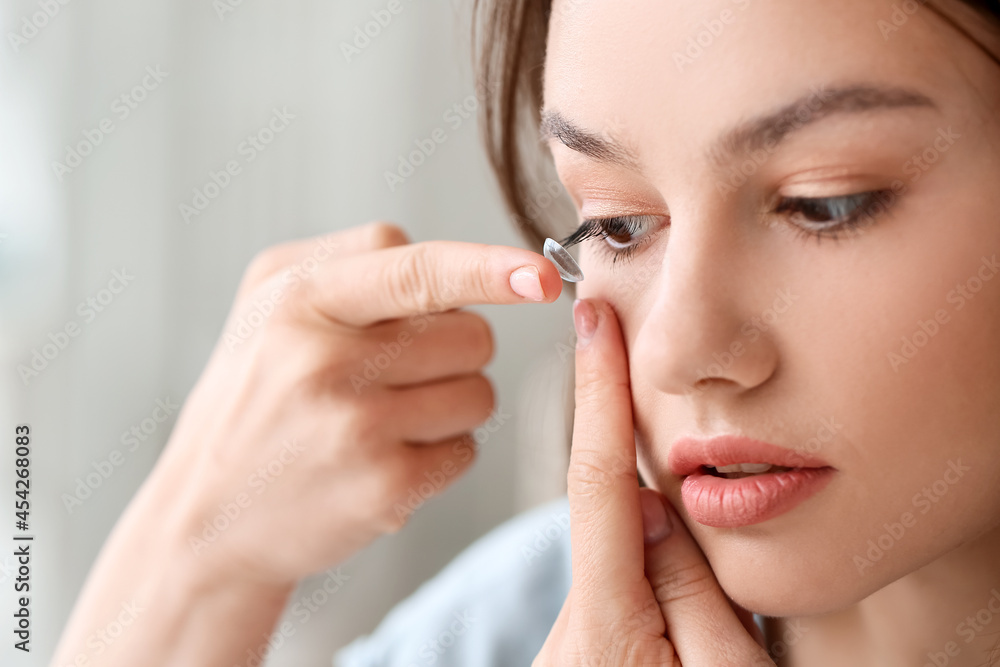 Young woman putting in contact lenses