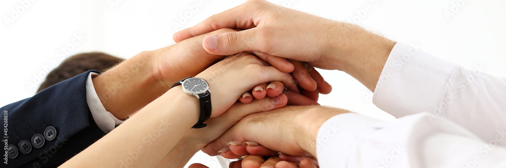 Group of people in suits crossed hands in pile Group of people in suits crossed hands in pile