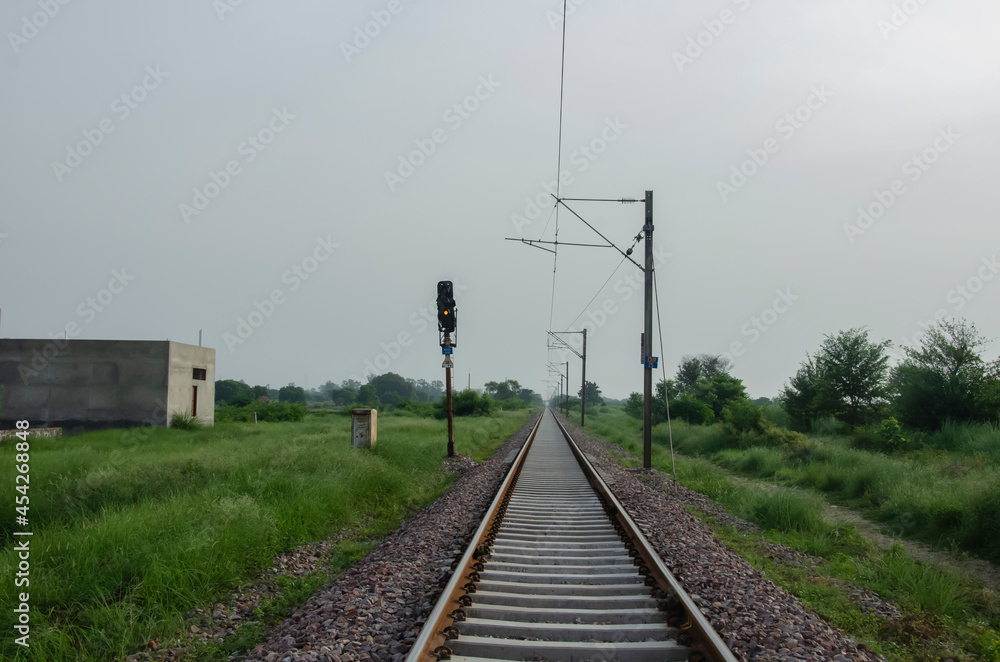 RAILWAY TRACK WITH LIGHT AND ELECTRIC POLE IN LANDSCAPE. INDIAN RAILWAY TRACK IN THE MORNING SUNLIGHT. RAILWAY TRACK WITH LIGHT AND ELECTRIC POLE IN LANDSCAPE. INDIAN RAILWAY TRACK IN THE MORNING SUNLIGHT.
