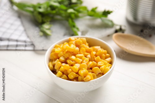 Bowl with corn kernels on light wooden background, closeup