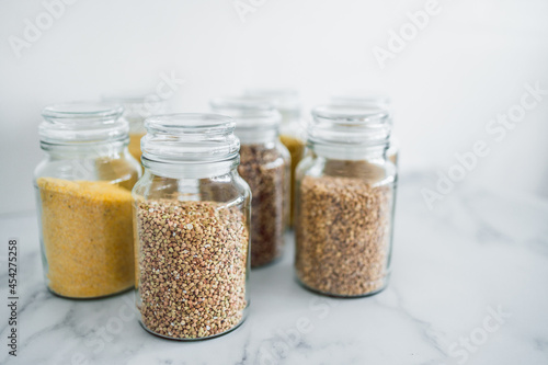 clear pantry jars with different types of grains in them including quinoa rice buckwheat couscous and barley, simple ingredients concept