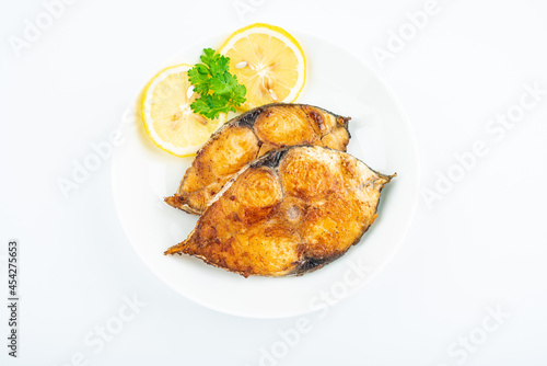 Pan-fried mackerel pieces on a plate on white background