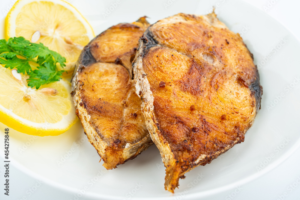Pan-fried mackerel pieces on a plate on white background Pan-fried mackerel pieces on a plate on white background