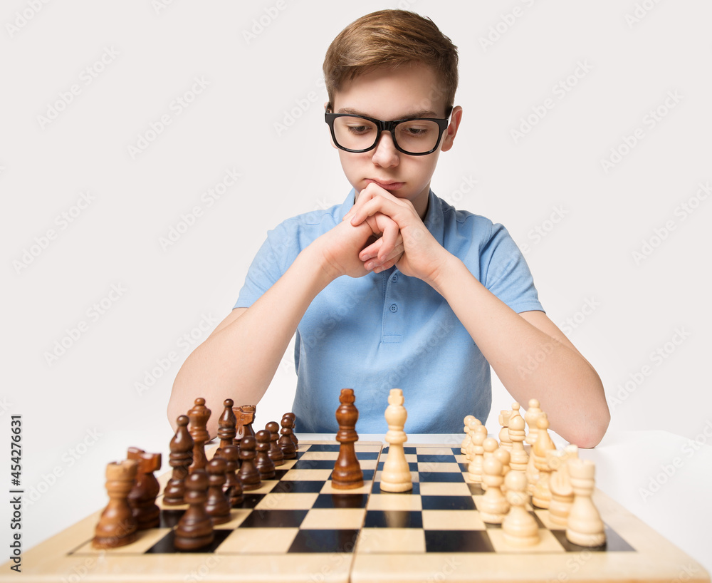 Pupil kid thinking about his next move in a game of chess. Concentrated  little boy sitting at the table and playing chess Stock Photo - Alamy