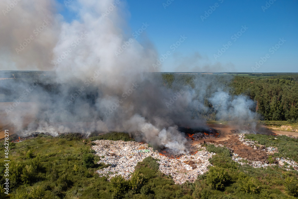 Burning garbage dump at summer. Polluting air with toxic gases