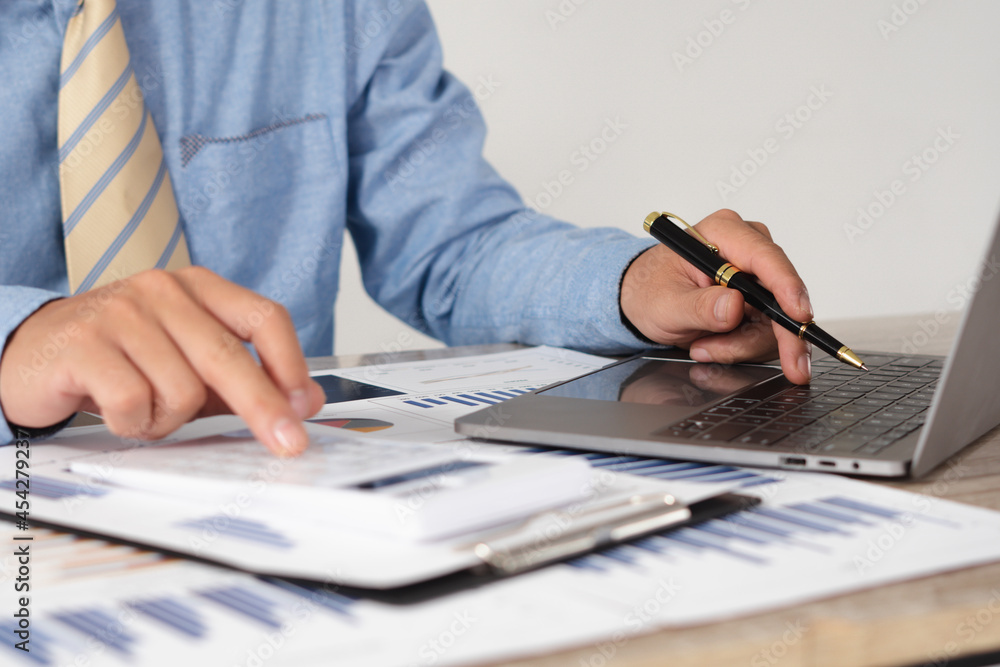 Fototapeta premium Businessman is deeply reviewing a financial report for a return on investment or investment risk analysis.