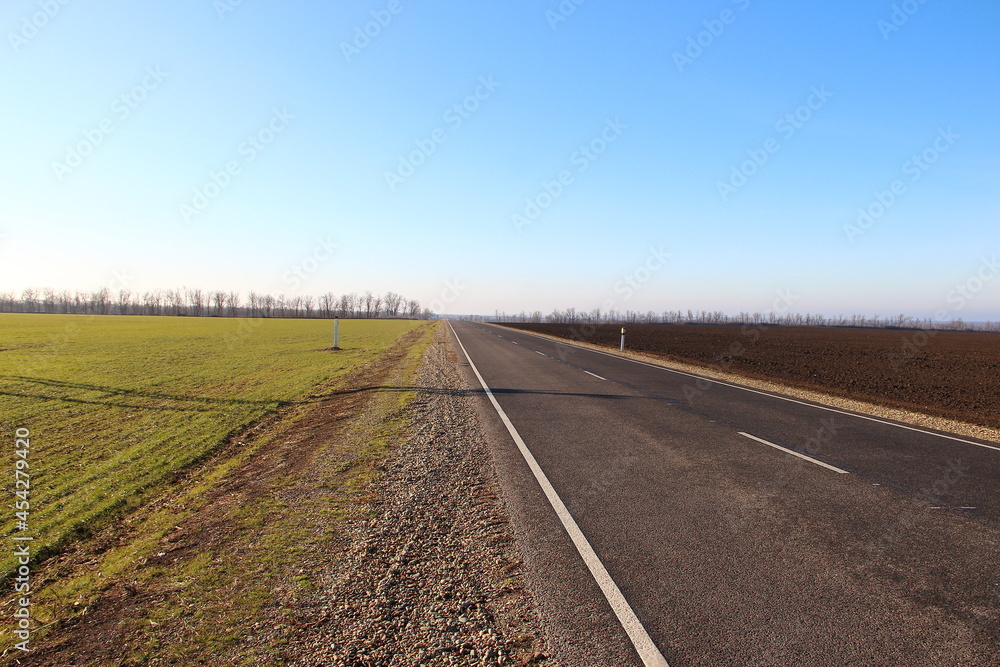 Asphalt road near agricultural fields and blue sky on a backround Asphalt road near agricultural fields and blue sky on a backround