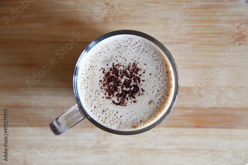Transparent mug of cappuccino with delicate froth with chocolate top view