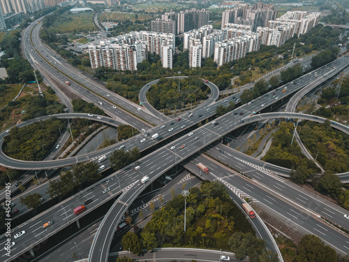 Top up aerial drone view of elevated road and traffic junctions in Chinese metropolis city during sunny day golden hour. Modern construction design of traffic ways to avoid traffic jams. Few vehicles.