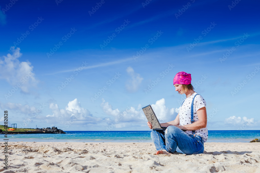 Young hipster woman working on laptop at the beach