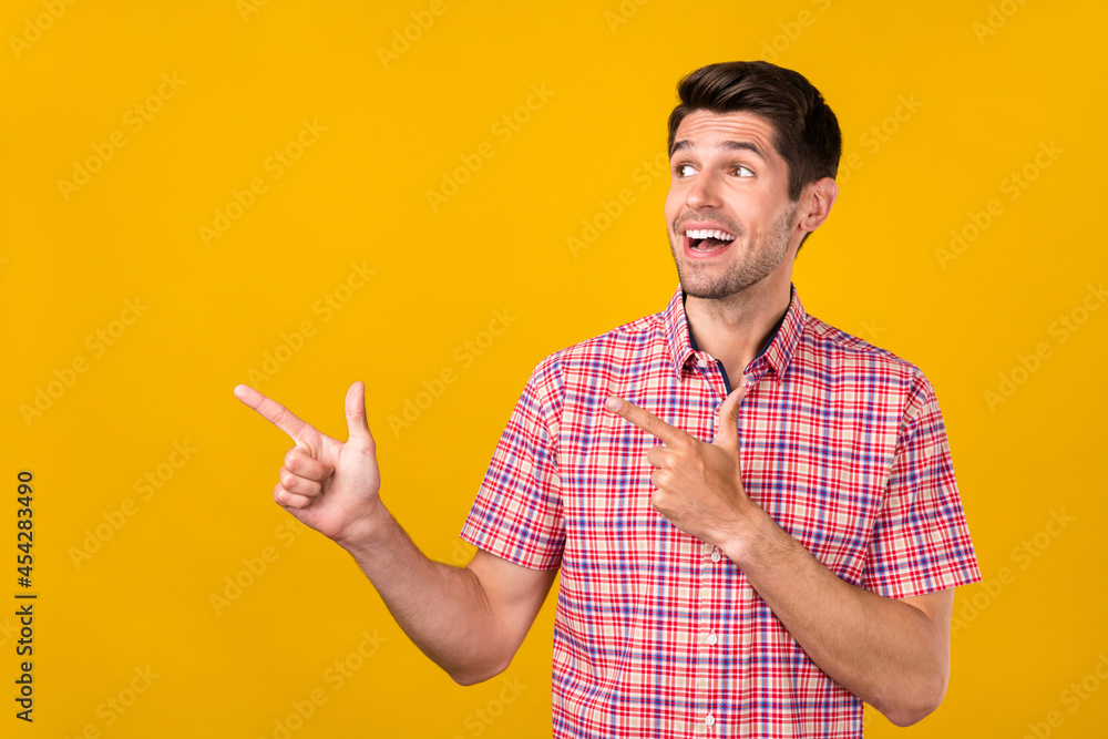 Photo of amazed curious young happy man point fingers empty space sale look isolated on yellow color background Photo of amazed curious young happy man point fingers empty space sale look isolated on yellow color background