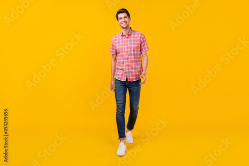 Full length body size view of attractive cheerful guy wearing denim strolling isolated over bright yellow color background