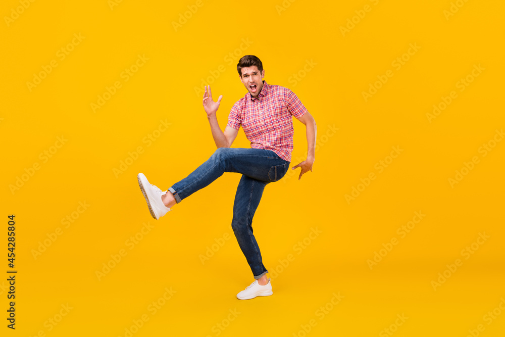 Full size photo of happy cheerful crazy man dance funky raise leg funny isolated on yellow color background