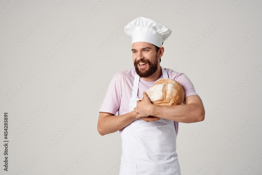 a man in a white apron baker holding bread in the hands of cooking a man in a white apron baker holding bread in the hands of cooking