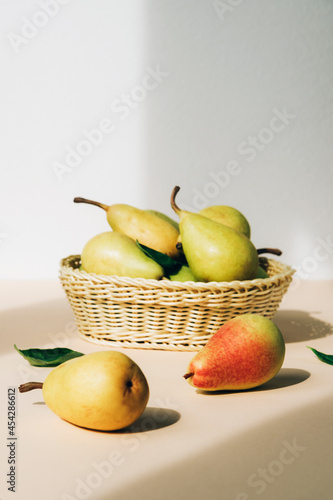 Fresh ripe pears in the basket on beige table. Healthy vegan food. Close up