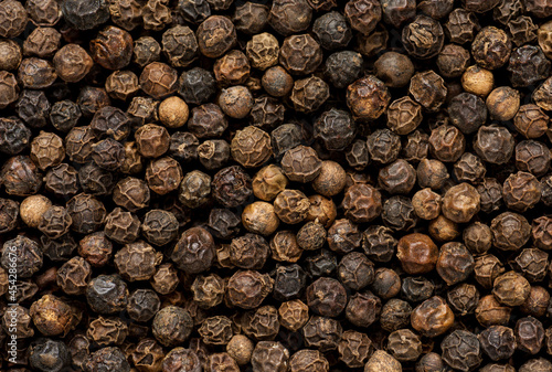 Black pepper grains as background close up
