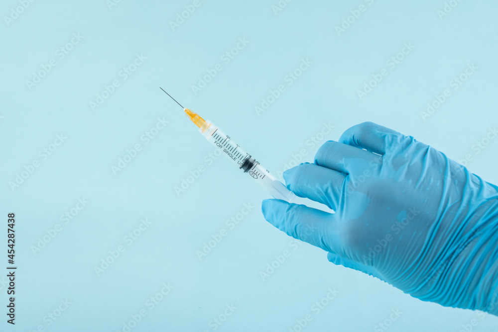 Gloved doctor holding a syringe for injection Gloved doctor holding a syringe for injection