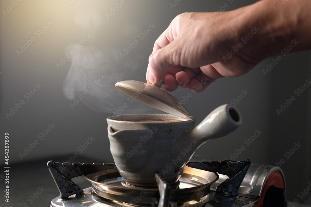 Soft focus, Hand opening cauldron with Chinese tea. Japanese Tea - Hot Teapot.