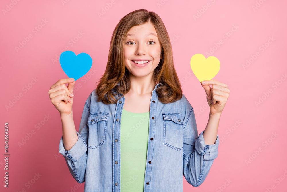 Photo portrait girl smiling showing two paper hearts isolated pastel pink color background Photo portrait girl smiling showing two paper hearts isolated pastel pink color background