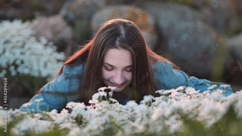 Long-haired girl sniffs white flowers and smiles. Long-haired girl sniffs white flowers and smiles.