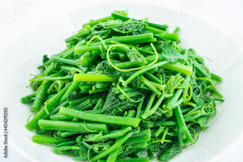 A dish of fried pumpkin vines on white background