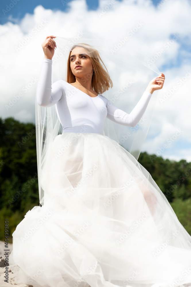 Bride in white dress outdoor on the sand and blue sky background Bride in white dress outdoor on the sand and blue sky background