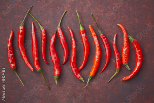 Fresh red hot chili peppers in the centre of reddish copper metal background, top view, copy space, flat lay.