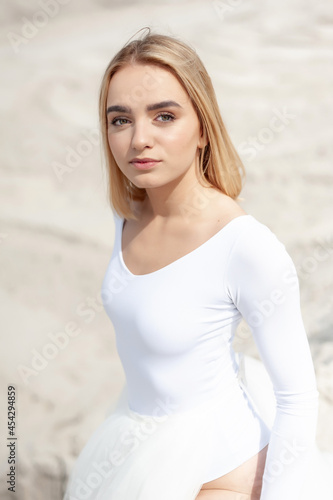 Beautiful young smiling blonde woman posing on sand dune