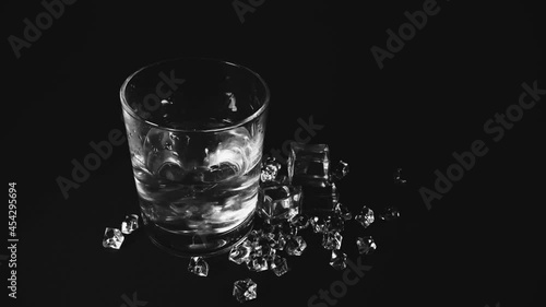A glass of transparent glass with cubes of colorless liquid ice floating in it