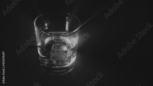A glass of transparent glass with cubes of colorless liquid ice floating in it