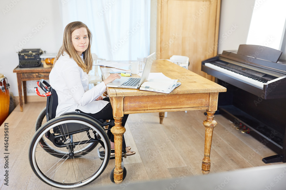 Frau mit Behinderung im Rollstuhl am Laptop im Wohnzimmer Frau mit Behinderung im Rollstuhl am Laptop im Wohnzimmer