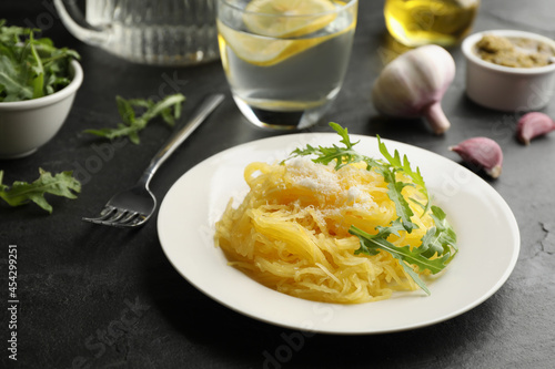 Tasty spaghetti squash with cheese and arugula served on black table