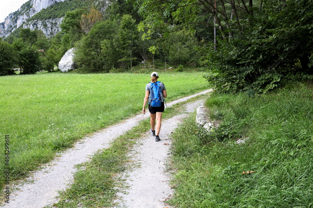 Blonde girl with hat and backpack walks trekking on an alpine trail in Trentino, Italy. Blonde girl with hat and backpack walks trekking on an alpine trail in Trentino, Italy.