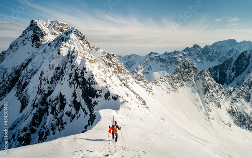 A skier is walking up the hill. Skitouring in Alps. Sunny weather. Hiking, adventure tourism, travel. Mountaineer backcountry ski walking in the mountains. © Pavel Kašák