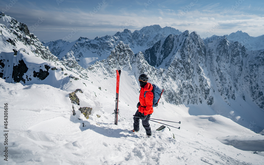 A skier is walking up the hill. Skitouring in Alps. Sunny weather. Hiking, adventure tourism, travel. Mountaineer backcountry ski walking in the mountains.
