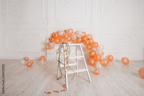 A festive scene with a white ladder and peach-colored balloons against a minimalistic background. photo