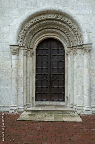 Metal doors of the Dmitrievsky Cathedral. White stone building  historical monument.