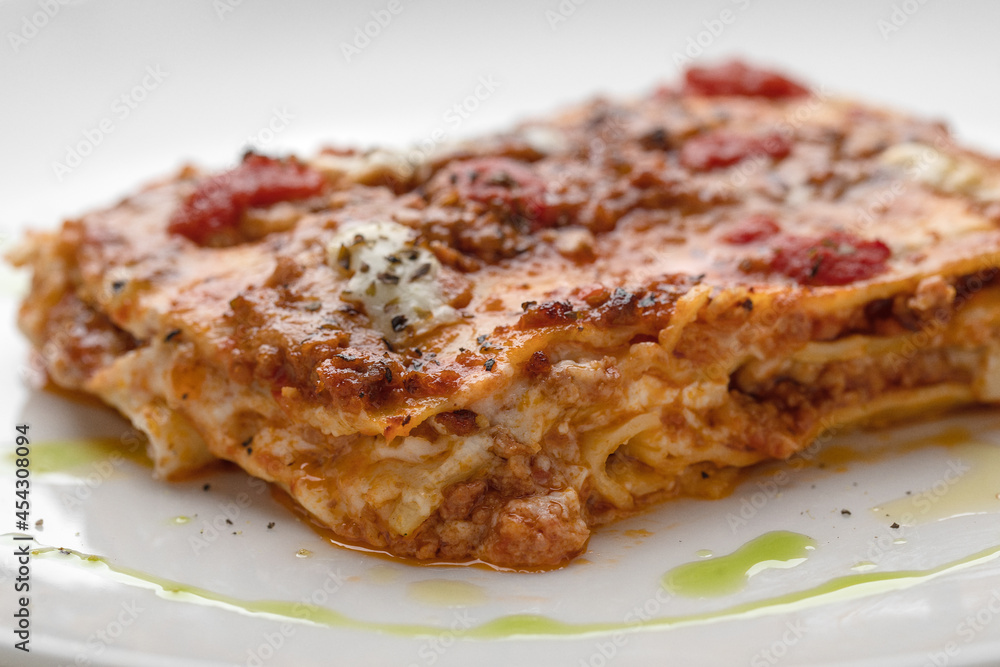 Take Out Creamy Lasagna with fresh mozzarella and tomatoes on white plate macro close up Take Out Creamy Lasagna with fresh mozzarella and tomatoes on white plate macro close up
