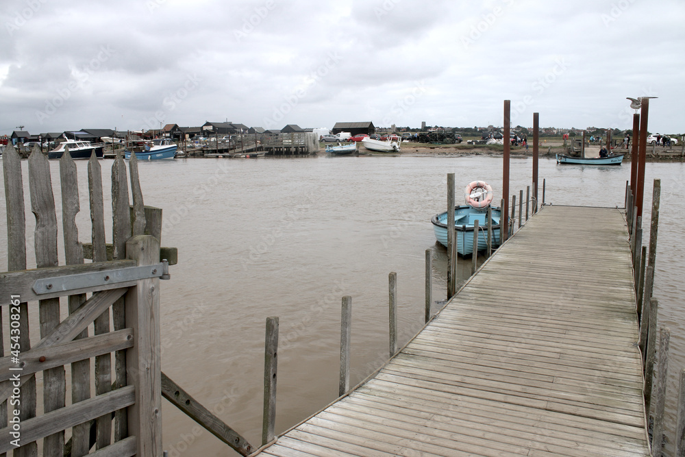 Landscape of ferry boat mooring platform across the river Blyth at Walberswick to Southwold in Suffolk East Anglia the estuary at high tide at the harbour with sailing boats and grey water and clouds Landscape of ferry boat mooring platform across the river Blyth at Walberswick to Southwold in Suffolk East Anglia the estuary at high tide at the harbour with sailing boats and grey water and clouds