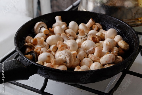 champignons are fried in a black pan close up