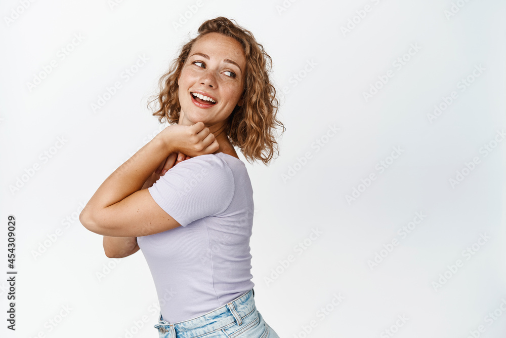 Beautiful blond woman turn back, looking behind her shoulder and smiling, reading copy space, standing over white background Beautiful blond woman turn back, looking behind her shoulder and smiling, reading copy space, standing over white background