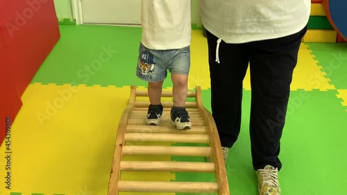 The child's legs in blue sneakers move on a special simulator to restore health