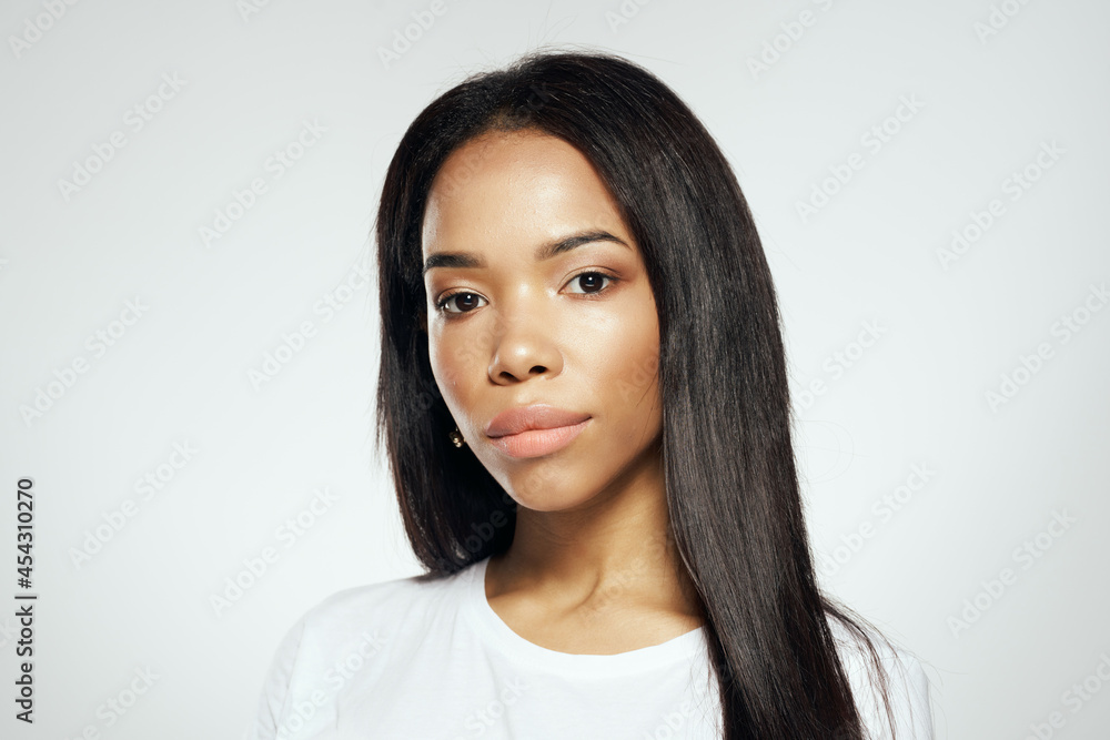 attractive woman of african appearance in a white t-shirt straightens her hair earrings attractive woman of african appearance in a white t-shirt straightens her hair earrings