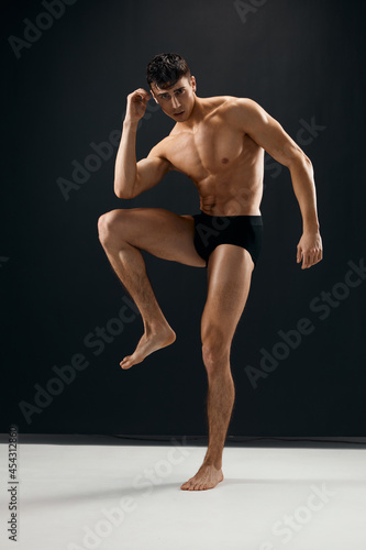 man with a muscular body in black shorts posing dark background