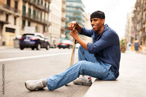 African man with skateboard. Young handsome man having fun outdoors.