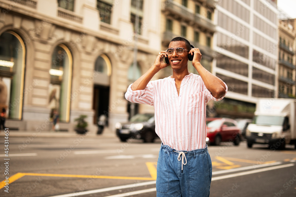 Cheerful guy with the headphones. Young african man listening the music outdoors