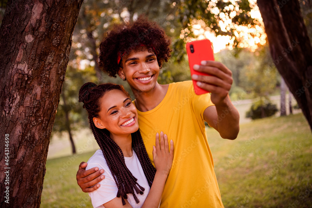 Photo portrait young couple wearing casual outfit smiling embracing in park taking selfie