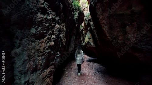 One woman inside a cave against cloudy sky. Scenic rear view of a explorer walking in outstanding caves against beautiful landscape in Cuevas de Zaen, Spain. Europe destinations. photo