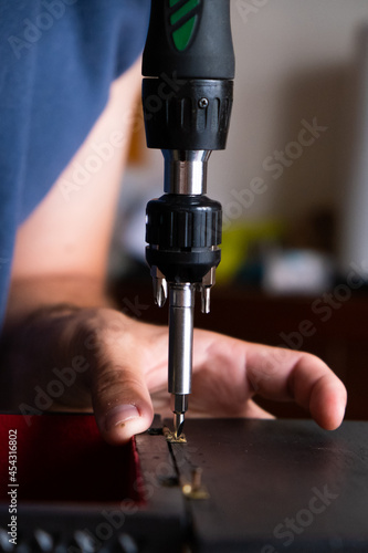 Close-up of a man screwing a hinge into a wooden box. Concept carpentry at home, furniture restoration